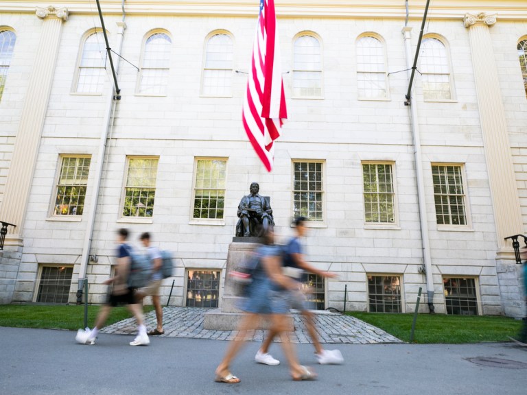 Students walking by the John Harvard statue