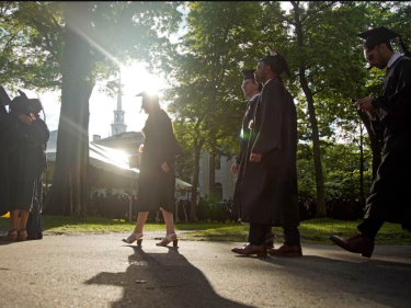 Students in graduation outfits walking in Harvard Yard