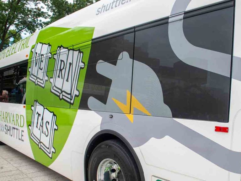 a bus with a green Harvard shield that reads "100% electric"