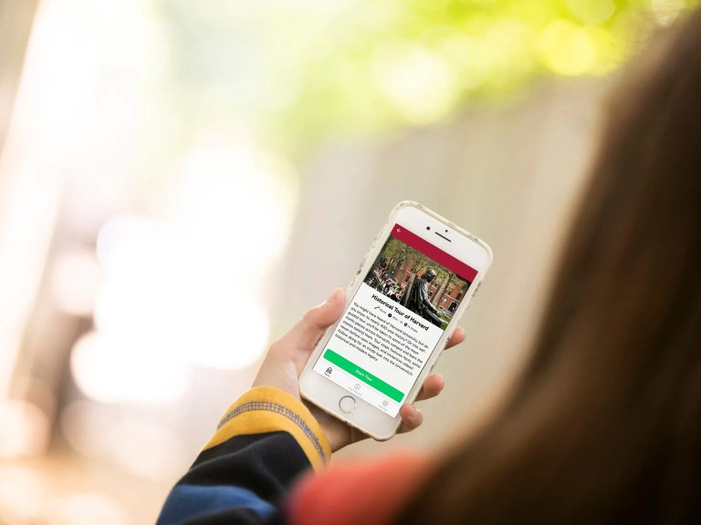 A person holding a cellphone with a Harvard app on it