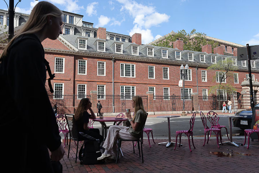 women sitting at a cafe in Harvard Square while another woman walks by.