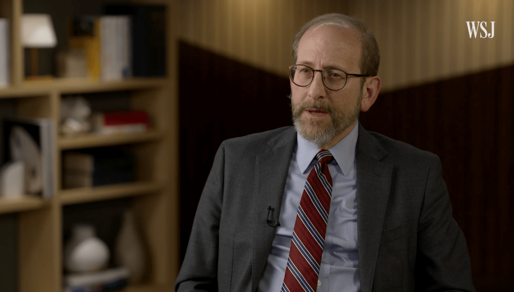Alan Garber speaking to an interviewer in a suit and tie.