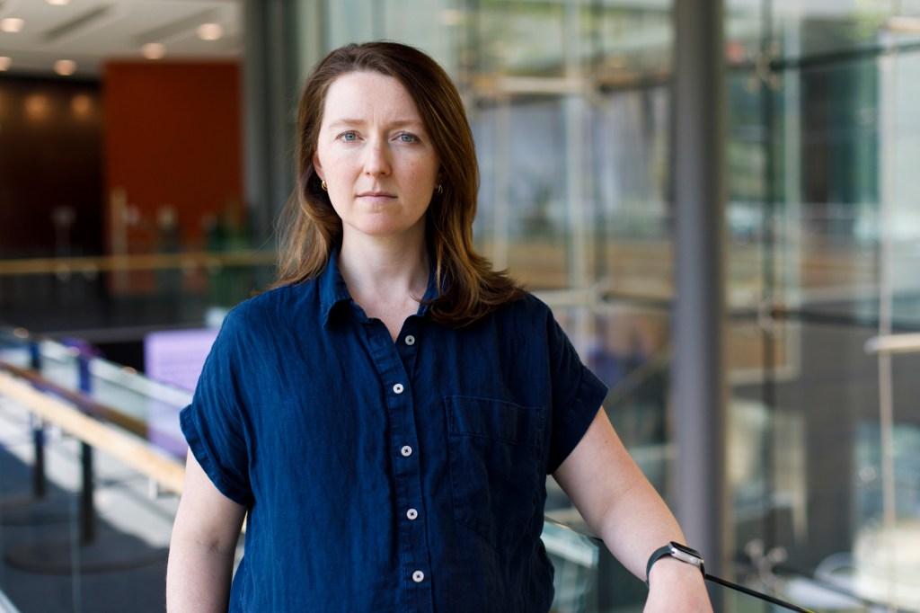 Woman in a blue dress looks at the camera.