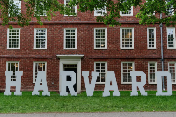 Larger white letters stand against Mass Hall. They spell out "Harvard".