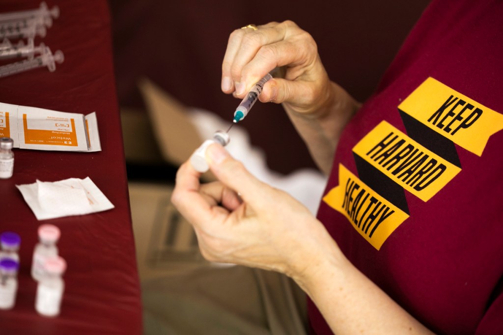 person with a syringe and a "keep Harvard healthy" shirt