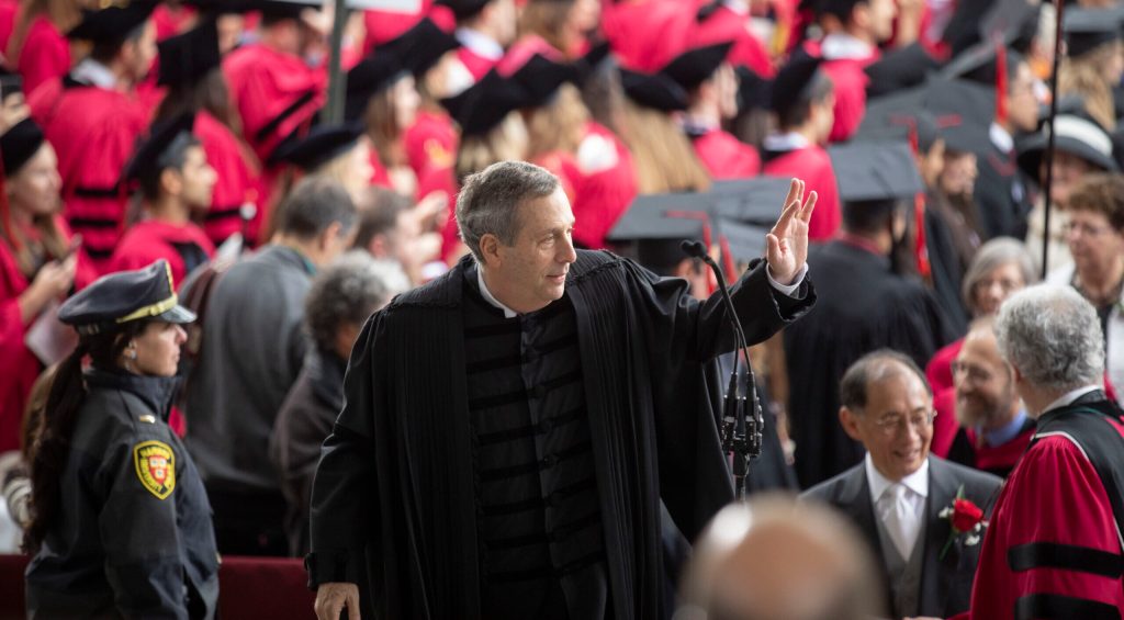 Larry Bacow waiving to a Commencement crowd