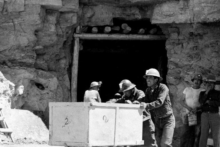 A black and white photo of native american men pushing mining carts