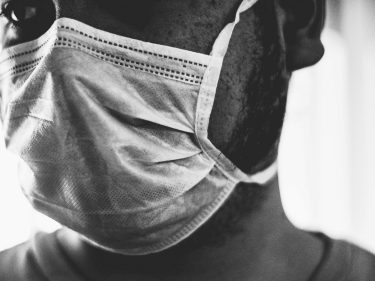 A black and white photo of a man wearing a face covering