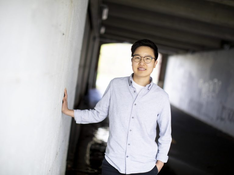 A student leans against a stone pillar