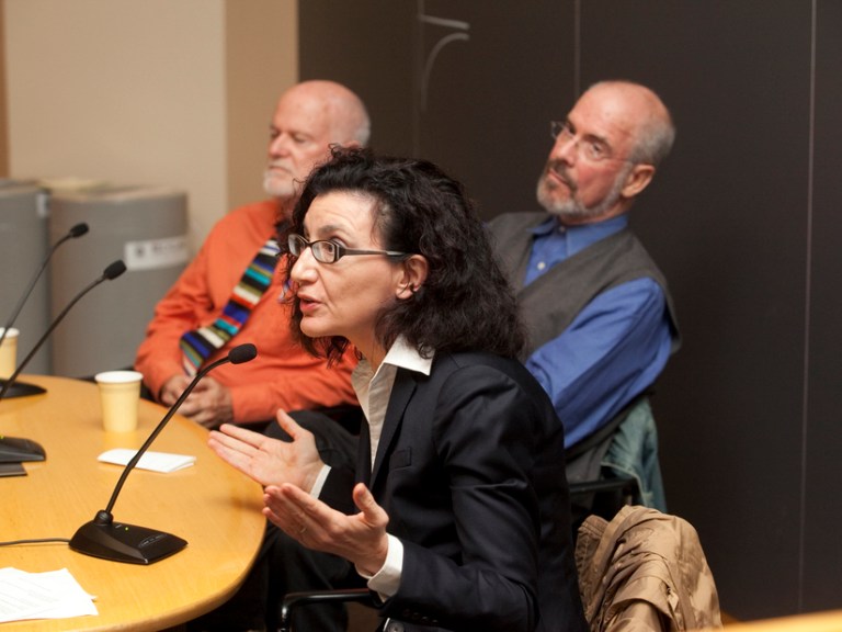 Three people on a panel talking into microphones