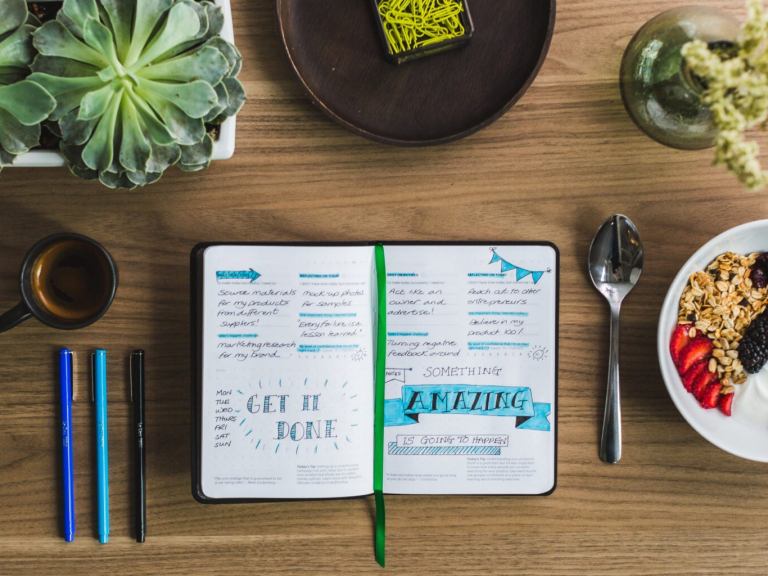 A bullet journal and some food on a desk