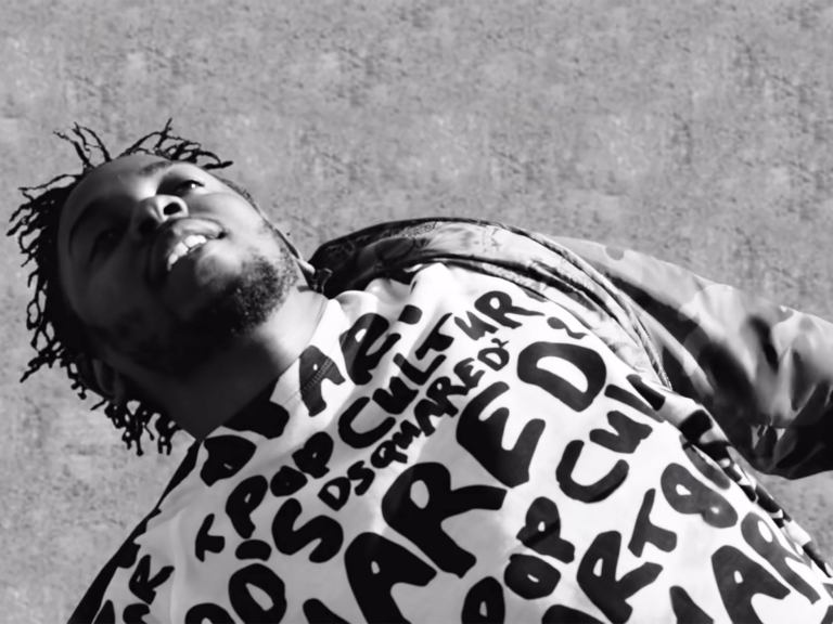 A black and white photo of a man wearing a sweatshirt with writing on it
