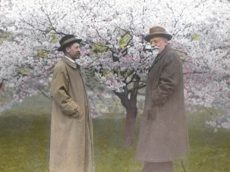 An old photograph of two men standing in front of a cherry blossom tree
