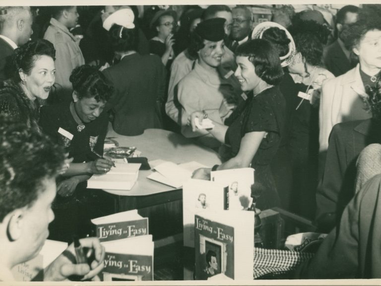 A woman signing books for a large crowd