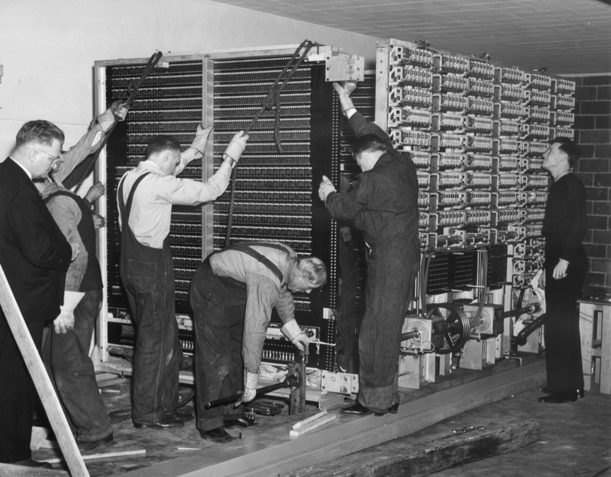 People installing a very large and very old computer