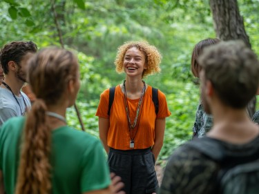 A woman leading a group through the woods