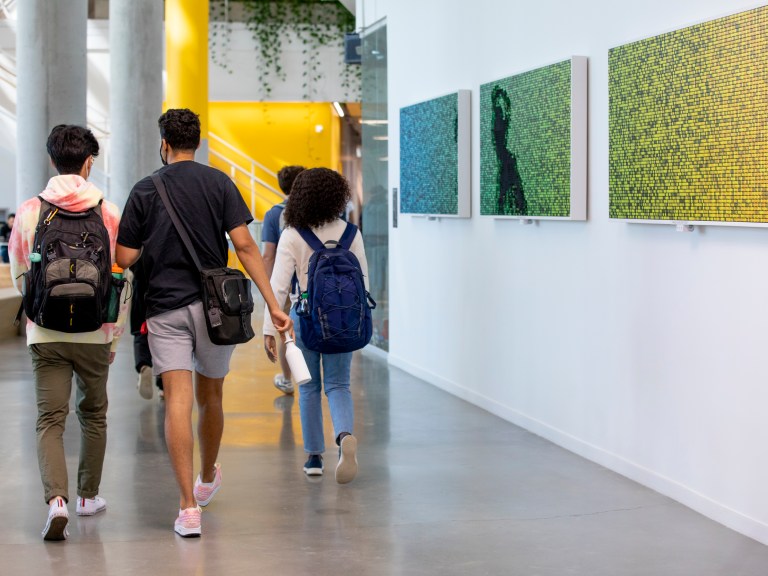 Students wearing backpacks walk down a corridor