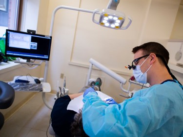 A dentist works on a patient in an exam room