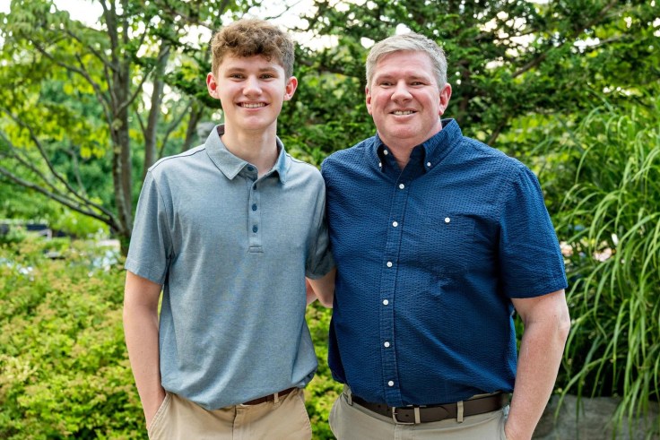 A father and son stand together outside