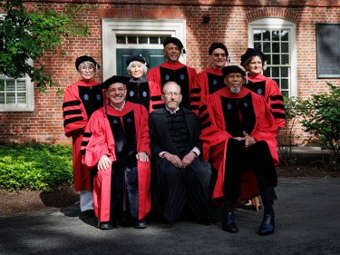 Seven honorary degree recipients in regalia sit together with President Garber