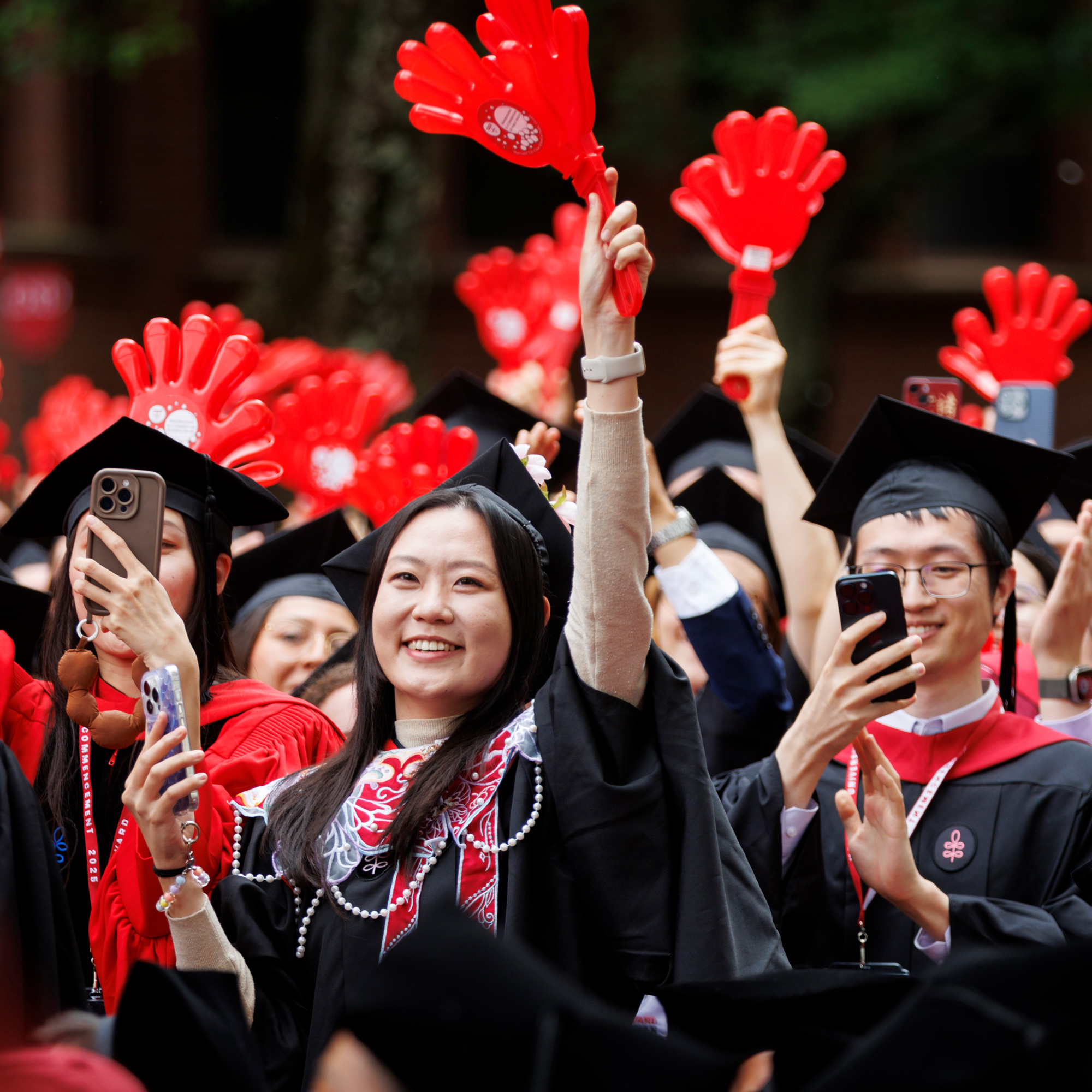 Graduates from the T.H. Chan School of Public Health show off their red hand-shaped clappers.